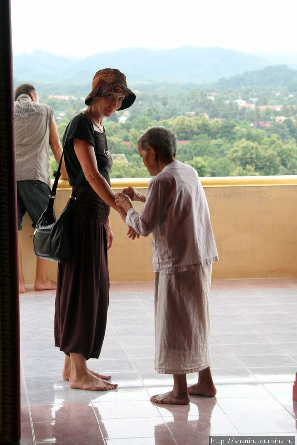 Монахиня — охранница встречает и провожает немногочисленных туристов на входе Луанг-Прабанг, Лаос