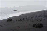 Черный вулканический песок на пляже выглядит очень необычно и в пасмурную погоду создает впечатление черной белой картины.