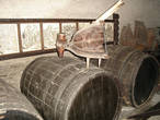 Осмотр начинается с подвала, где находится винный погреб с бочками. За ними на стене гравюры с изображением процесса виноделия.