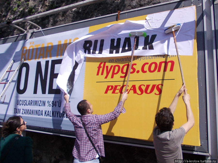 заклеивают официальные рекламы на Бесикташе Стамбул, Турция