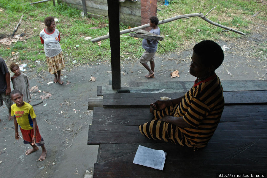 В это время костер уже успел разгореться. На заднем плане беременная женщина несет дрова. Папуа, Индонезия