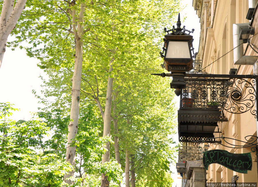 На главном проспекте Тбилиси среди листвы платанов можно рассмотреть эффектные вывески, решетки балконов и фонари прошлого века. Тбилиси, Грузия