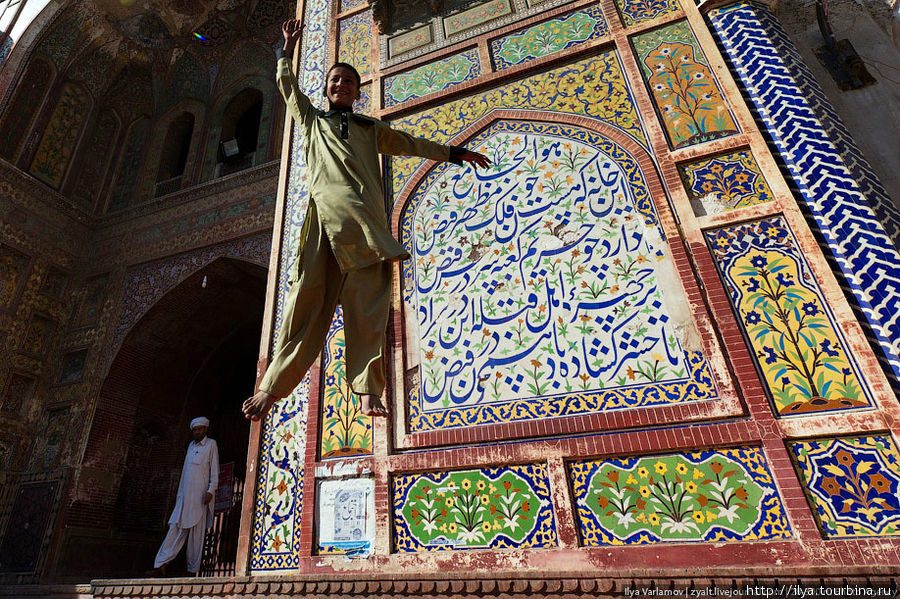 Мальчик прыгает на батуте напротив входа в мечеть. Лахор, Пакистан