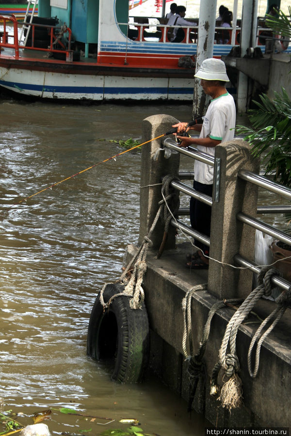 В реке у пристани Сатихорн рыба пока водится. По крайней мере рыбак на это очень надеется. Бангкок, Таиланд