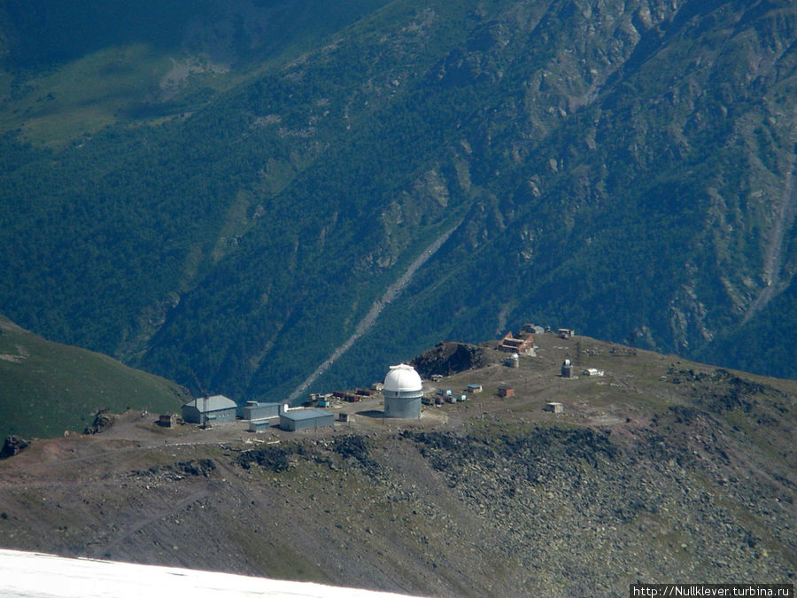 Недалеко, справа и чуть ниже видна Обсерватория Пик Терскол — международная астрономическая обсерватория, основанная в 1980 году. Кабардино-Балкария, Россия