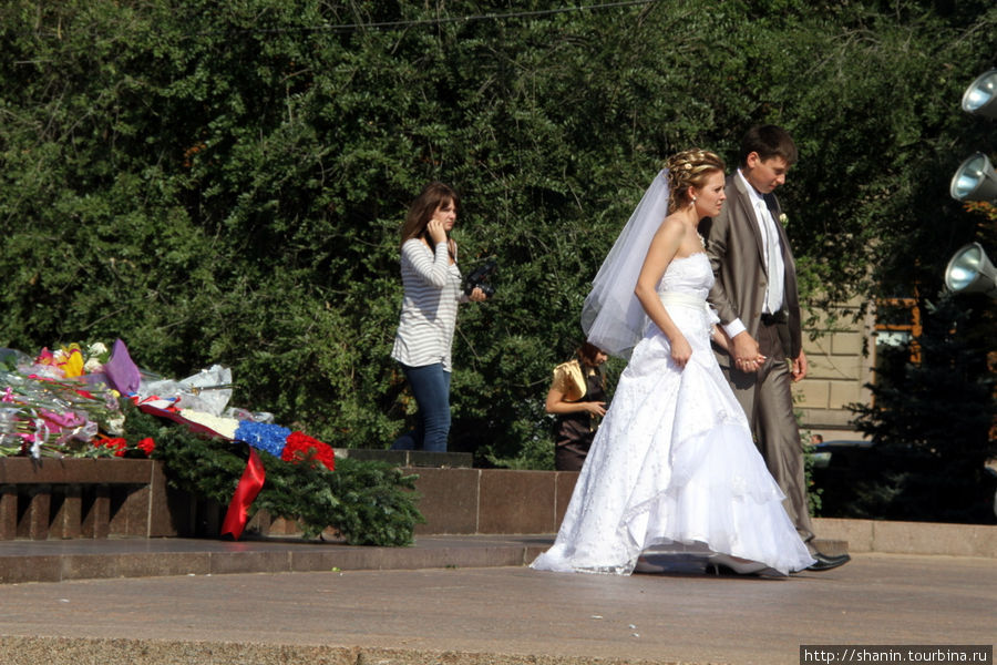 Жених с невестой у вечного огня перед памятникам жертвам Гражданской войны в Вогограде Волгоград, Россия