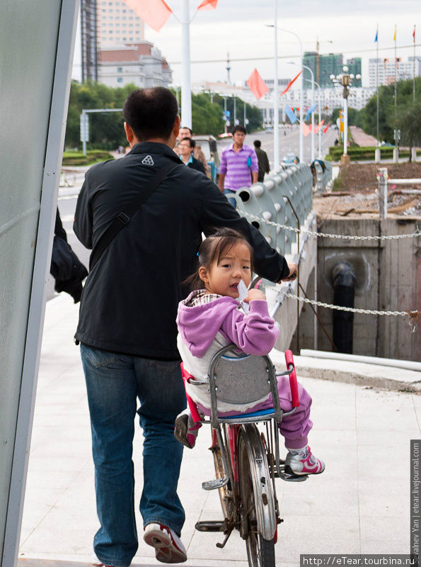 Удивленный ребенок в велосипедном кресле Хэйхэ, Китай