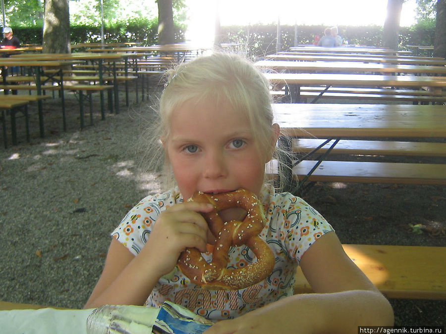 Дочка с аппетитом поглощает брецели в биргардене Обершлайсхайм, Германия