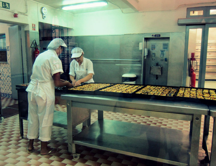 Через стекло можно посмотреть за частью процесса приготовления пирожных. Лиссабон, Португалия